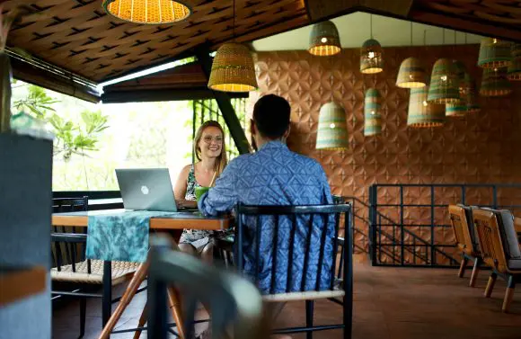 Couple of millennial friends studying together in bohemian cafe in Bali serving fair-trade organic coffee